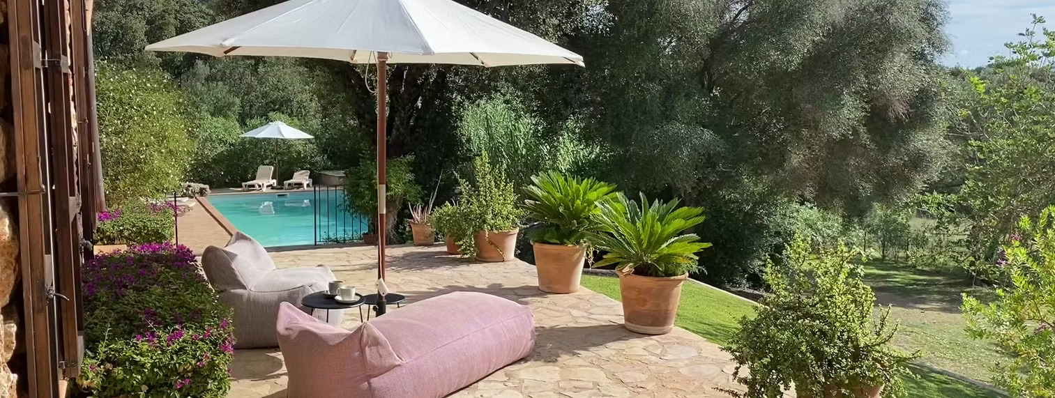 Poolterrasse mit Sonnenschirm und Loungemöbeln